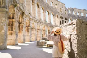 Woman,in,hat,stands,and,looking,on,coliseum,in,pula